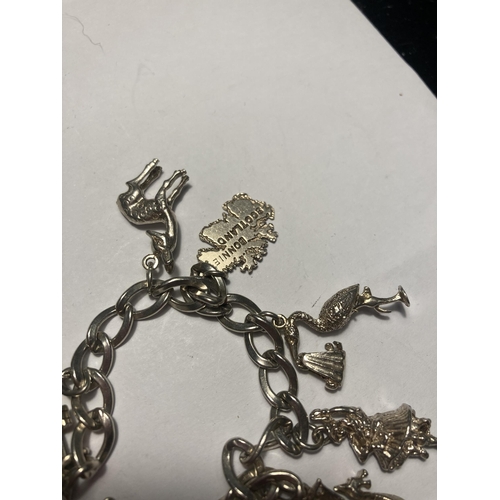 514 - A SILVER CHARM BRACELET WITH EIGHT CHARMS AND A HEART PADLOCK