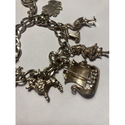 514 - A SILVER CHARM BRACELET WITH EIGHT CHARMS AND A HEART PADLOCK