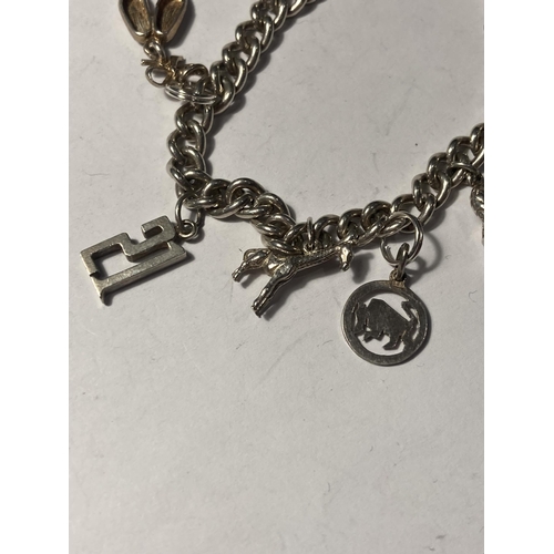 682 - A SILVER CHARM BRACELET WITH NINE CHARMS AND A HEART PADLOCK