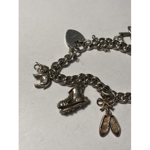 682 - A SILVER CHARM BRACELET WITH NINE CHARMS AND A HEART PADLOCK