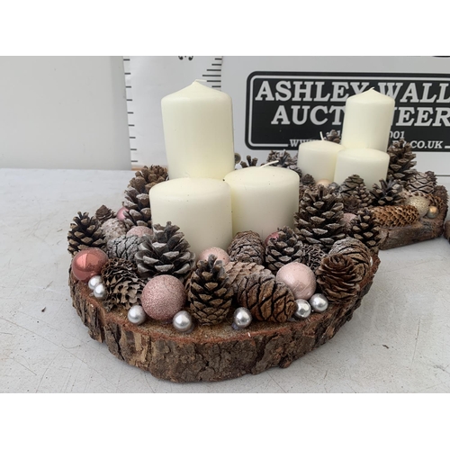 110 - THREE LARGE PILLAR CANDLE ARRANGEMENTS WITH FIR CONES ON A WOODEN BASE + VAT. TO BE SOLD FOR THE THR... 