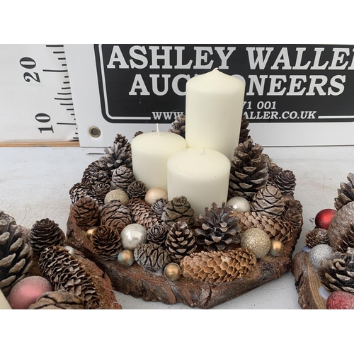 110 - THREE LARGE PILLAR CANDLE ARRANGEMENTS WITH FIR CONES ON A WOODEN BASE + VAT. TO BE SOLD FOR THE THR... 