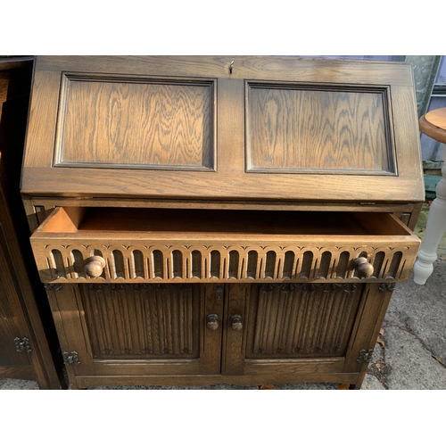 3028 - A MODERN OAK BUREAU WITH LINENFOLD DOORS TO THE BASE, 33