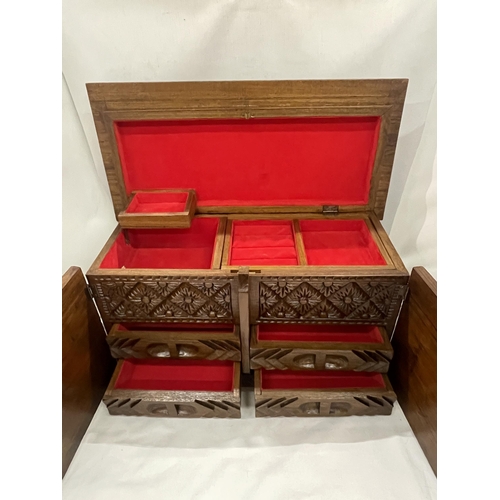 30 - A HEAVILY CARVED JEWELLERY BOX WITH TWO DOORS REVEALING FOUR LINED DRAWERS AND A LIFT UP LID WITH LI... 