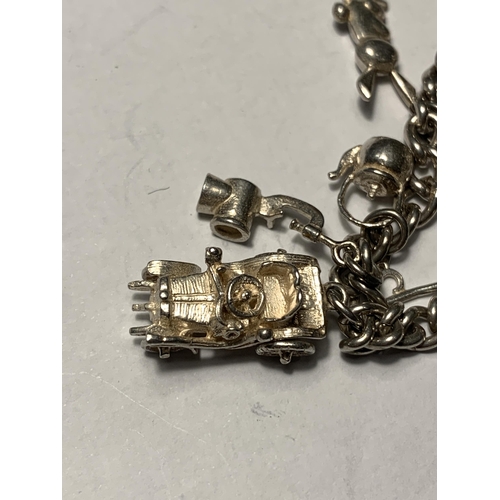 711 - A SILVER CHARM BRACELET WITH ELEVEN CHARMS AND A HALLMARKED BIRMINGHAM SILVER HEART PADLOCK