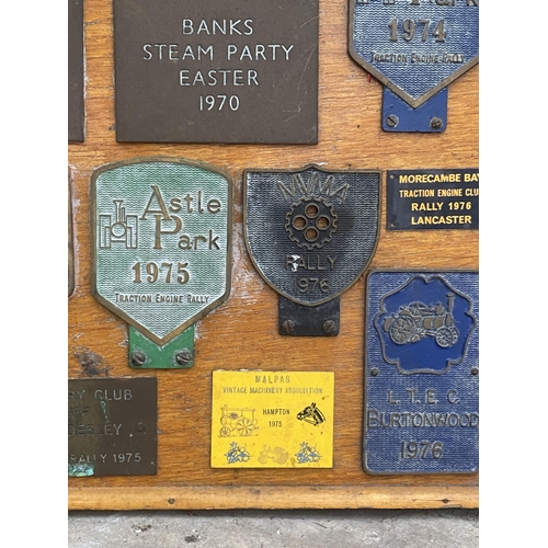 1506 - A WOODEN BOARD DISPLAYING A LARGE QUANTITY OF COMMEMERATIVE BRASS PLAQUES FROM VARIOUS STEAM RALLIES