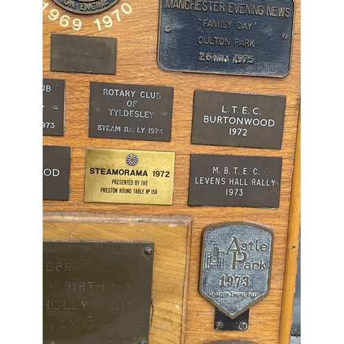 1506 - A WOODEN BOARD DISPLAYING A LARGE QUANTITY OF COMMEMERATIVE BRASS PLAQUES FROM VARIOUS STEAM RALLIES