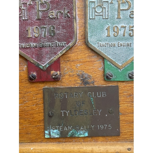 1506 - A WOODEN BOARD DISPLAYING A LARGE QUANTITY OF COMMEMERATIVE BRASS PLAQUES FROM VARIOUS STEAM RALLIES