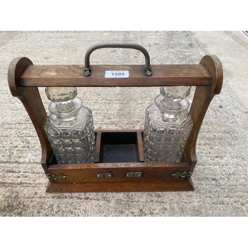 1595 - A VINTAGE OAK TANTALUS DECANTER HOLDER WITH TWO GLASS DECANTERS AND SILVER PLATE DETAIL