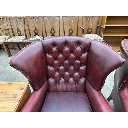 2878 - A PAIR OF MODERN BUTTON-BACK WINGED OXBLOOD FIRESIDE CHAIRS