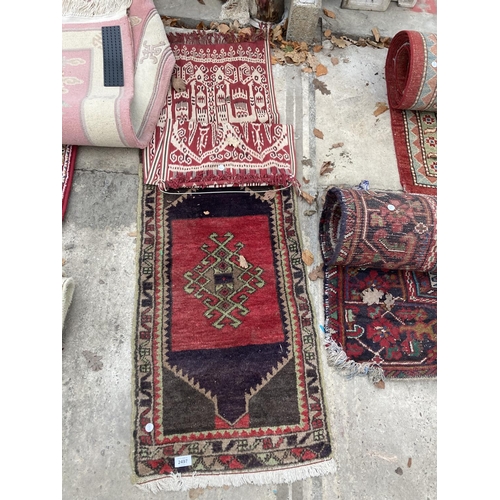 2497 - A SMALL RED PATTERNED FRINGED RUG AND A SMALL RED PATTERNED WALL HANGING