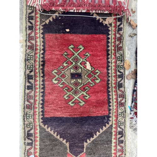 2497 - A SMALL RED PATTERNED FRINGED RUG AND A SMALL RED PATTERNED WALL HANGING