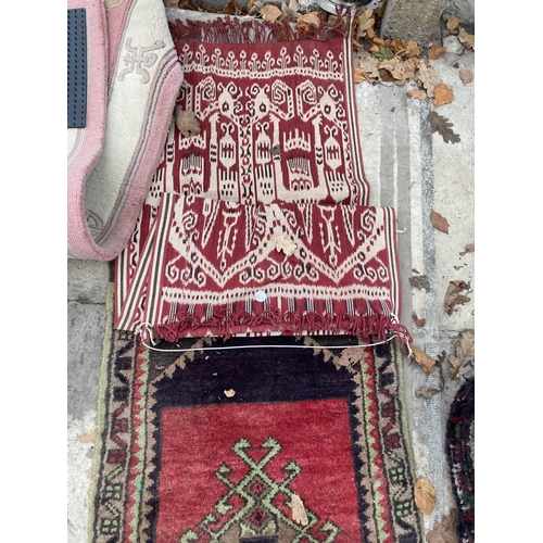 2497 - A SMALL RED PATTERNED FRINGED RUG AND A SMALL RED PATTERNED WALL HANGING