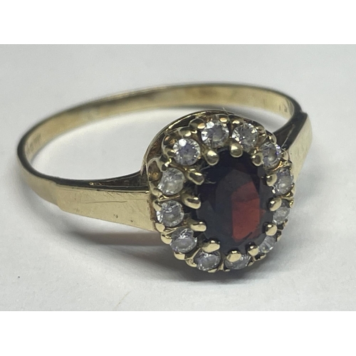 514 - A 9 CARAT GOLD RING WITH CENTRE GARNET SURROUNDED BY CUBIC ZIRCONIAS SIZE R/S