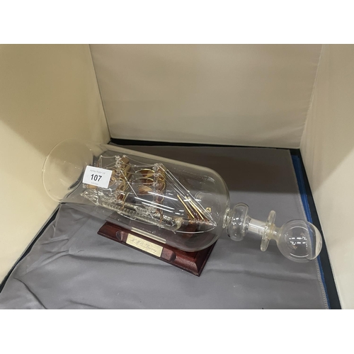 107 - A SHIP IN A BOTTLE 'HMS DISCOVERY' ON A WOODEN STAND, HEIGHT 15CM, LENGTH 34CM