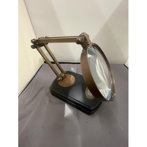 35 - A BRASS MAGNIFYING GLASS ON A WOODEN BASE