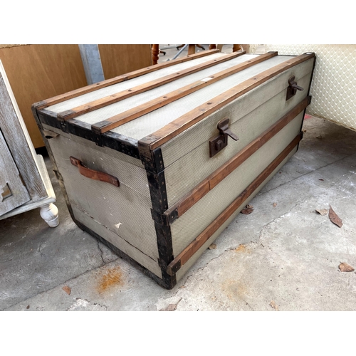 2706 - A COMPRESSED FIBRE TRAVELLING TRUNK, METAL BOUND WITH WOODEN SLATS