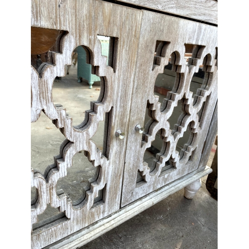 2707 - A LIMED CABINET WITH TWO MIRRORS, CARVED DOORS AND A SINGLE DRAWER 30