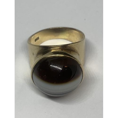 673 - A YELLOW METAL RING WITH TIGERS EYE STONE AND INDISTINCT MARK GROSS WEIGHT 7.95 GRAMS SIZE L/M