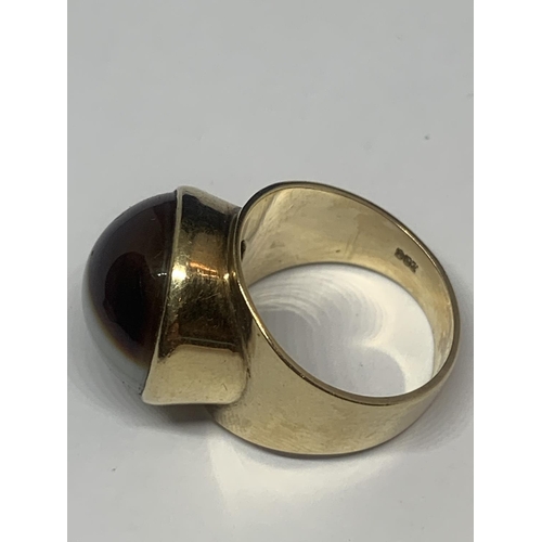 673 - A YELLOW METAL RING WITH TIGERS EYE STONE AND INDISTINCT MARK GROSS WEIGHT 7.95 GRAMS SIZE L/M