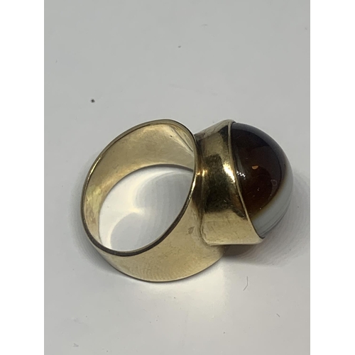 673 - A YELLOW METAL RING WITH TIGERS EYE STONE AND INDISTINCT MARK GROSS WEIGHT 7.95 GRAMS SIZE L/M