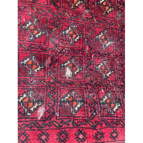 2490 - A SMALL RED PATTERNED FRINGED RUG