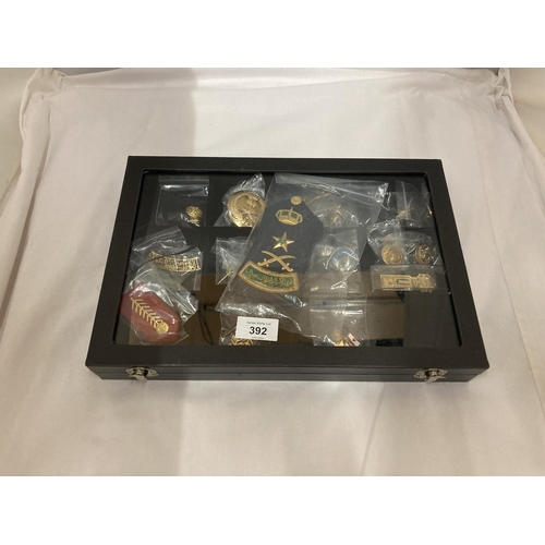 392 - A DISPLAY CASE CONSTAINING TWENTY FIVE GULF MEDALS AND BADGES INCLUDING A PAIR OF SAUDI ARMY EPAULET... 