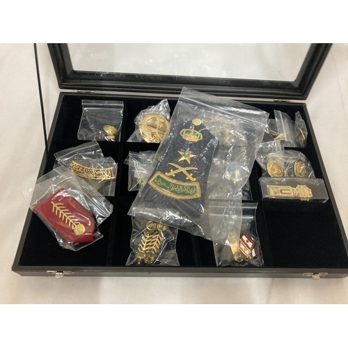 392 - A DISPLAY CASE CONSTAINING TWENTY FIVE GULF MEDALS AND BADGES INCLUDING A PAIR OF SAUDI ARMY EPAULET... 