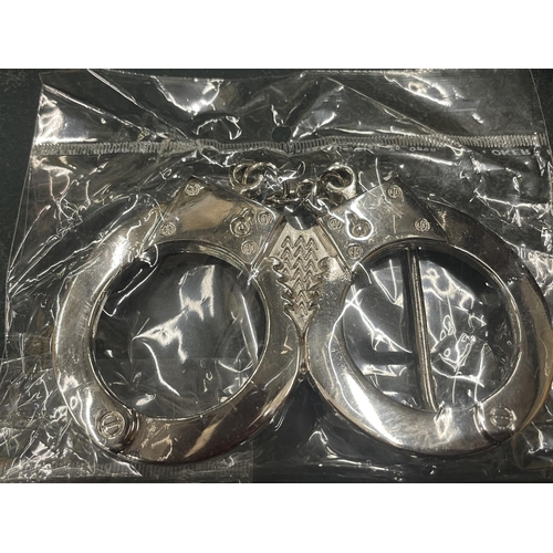 115 - FOUR ENAMEL AND CHROME BELT BUCKLES TO INCLUDE HAND CUFFS