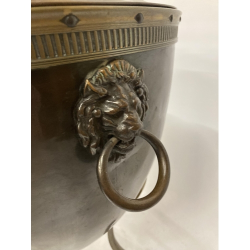 75 - A BRASS AND COPPER COAL BOX ON FOUR LEGS, WITH LION HEAD HANDLES, AN ACORN TOP AND LINER