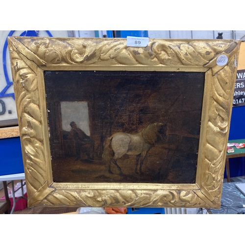 89 - A GILT FRAMED OIL ON BOARD OF A HORSE IN A STABLE