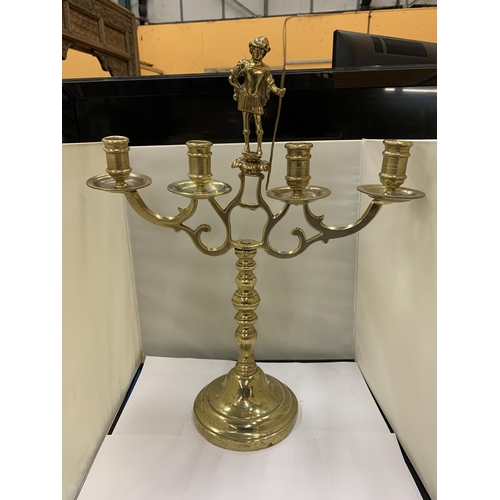 12 - A HEAVY BRASS CANDELABRA WITH A FIGURE HOLDING A STAFF