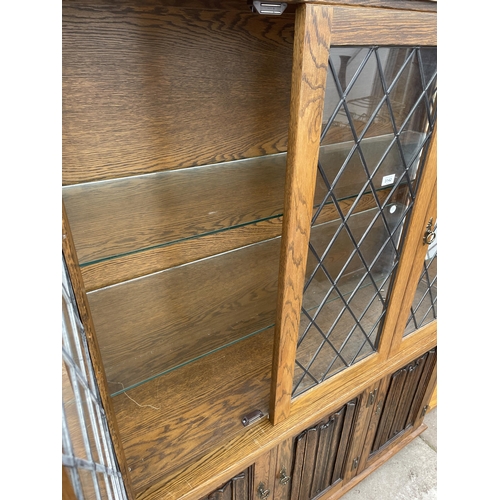 3142 - AN OAK OLD CHARM STYLE BOOKCASE WITH GLAZED AND LOADED UPPER PORTION AND LINEN-FOLD DOORS TO BASE - ... 