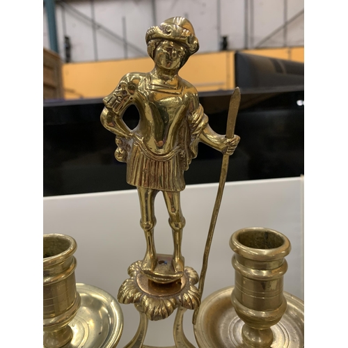 12 - A HEAVY BRASS CANDELABRA WITH A FIGURE HOLDING A STAFF