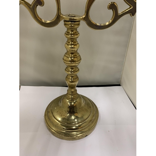 12 - A HEAVY BRASS CANDELABRA WITH A FIGURE HOLDING A STAFF