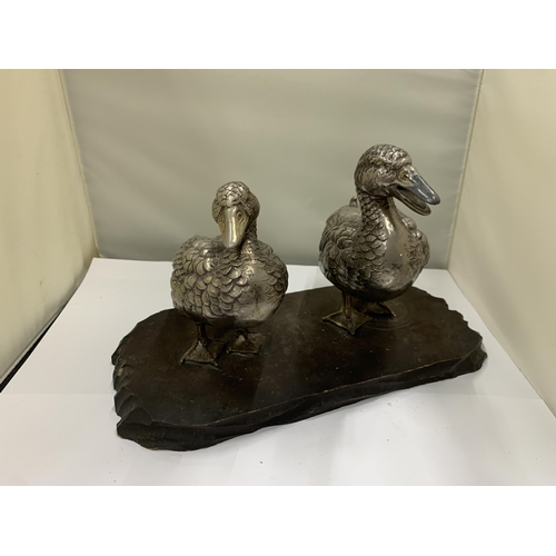 23 - A VINTAGE PAIR OF WHITE METAL DUCKS ON A WOODEN PLINTH