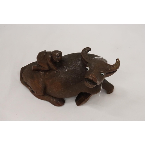 202 - AN ORIENTAL WOODEN CARVED WATER BUFFALO WITH CHILD RIDER, A/F TO LEG, HEIGHT 12CM, LENGTH 22CM