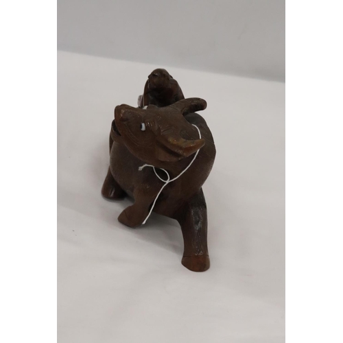 202 - AN ORIENTAL WOODEN CARVED WATER BUFFALO WITH CHILD RIDER, A/F TO LEG, HEIGHT 12CM, LENGTH 22CM