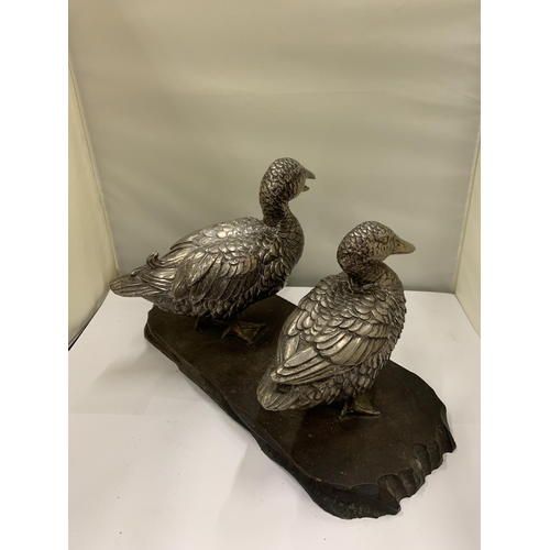 231 - A VINTAGE PAIR OF WHITE METAL DUCKS ON A WOODEN PLINTH