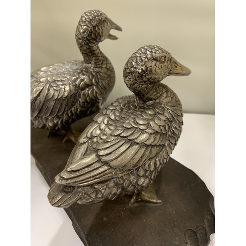 231 - A VINTAGE PAIR OF WHITE METAL DUCKS ON A WOODEN PLINTH