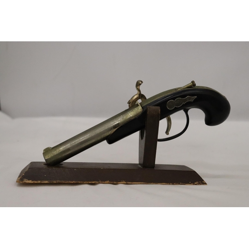 127 - A HEAVY, VINTAGE, PISTOL LIGHTER ON A WOODEN STAND, LENGTH 21CM