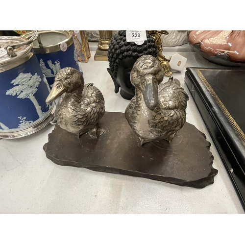 231 - A VINTAGE PAIR OF WHITE METAL DUCKS ON A WOODEN PLINTH