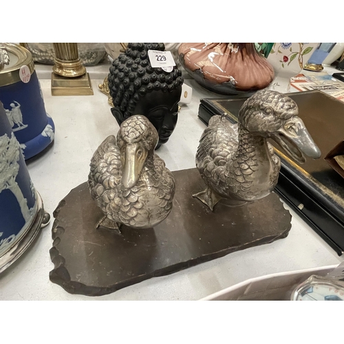 231 - A VINTAGE PAIR OF WHITE METAL DUCKS ON A WOODEN PLINTH