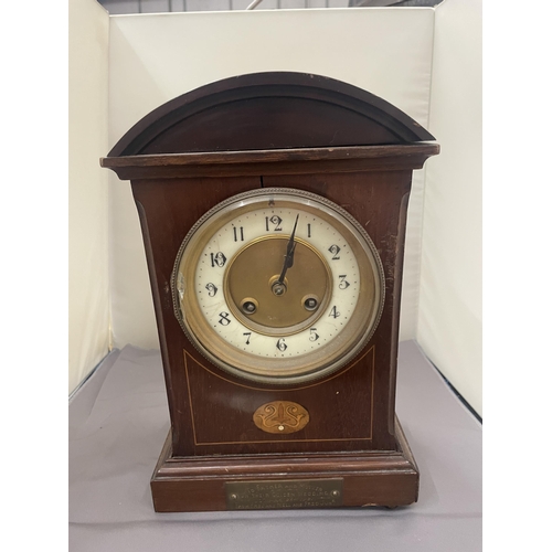 63 - A MAHOGANY INLAID MANTLE CLOCK WITH INSCRIPTION PLATE (A/F LEG MISSING)