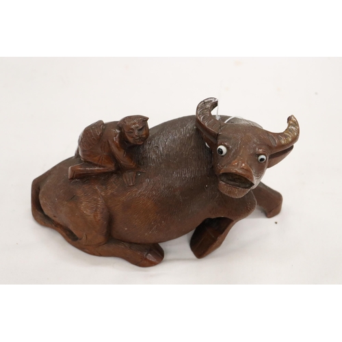 873 - AN ORIENTAL WOODEN CARVED WATER BUFFALO WITH CHILD RIDER, A/F TO LEG, HEIGHT 12CM, LENGTH 22CM