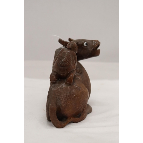 873 - AN ORIENTAL WOODEN CARVED WATER BUFFALO WITH CHILD RIDER, A/F TO LEG, HEIGHT 12CM, LENGTH 22CM