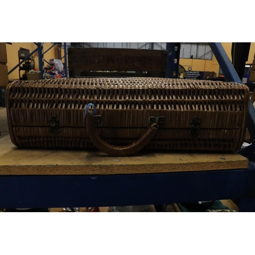 979 - A VINTAGE WICKER TRAVELLING CASE WITH STICKERS, HANDLE A/F