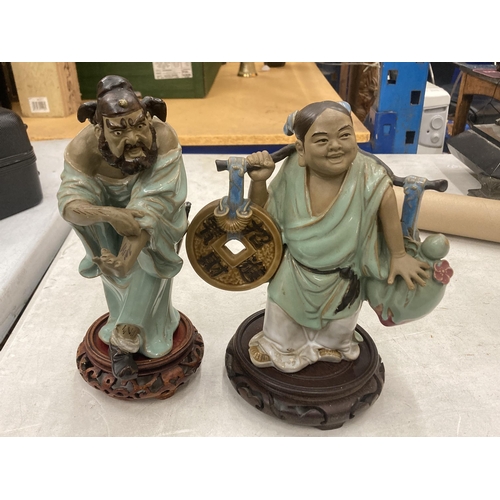 115 - TWO ORIENTAL CERAMIC FIGURES ON WOODEN STANDS, HEIGHTS 23CM