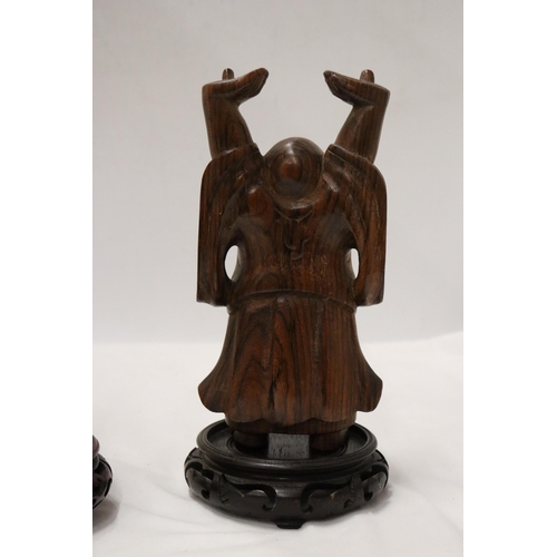 176 - TWO CARVED WOODEN ORIENTAL FIGURES TO INCLUDE A LAUGHING BUDDAH, ON STANDS