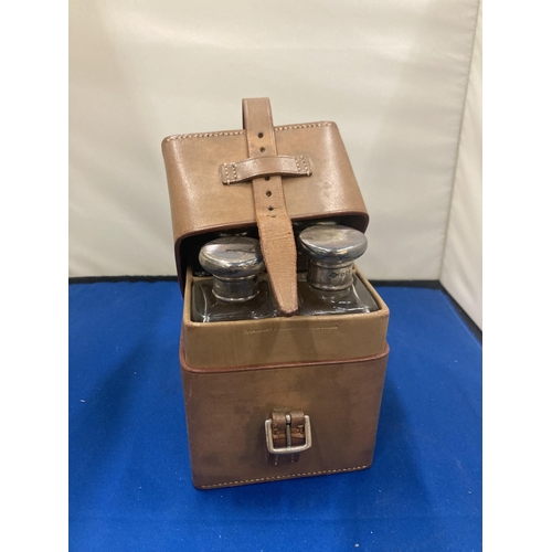 1 - A VINTAGE LEATHER CASE CONTAINING FOUR GLASS BOTTLES WITH HALLMARKED SILVER TOPS